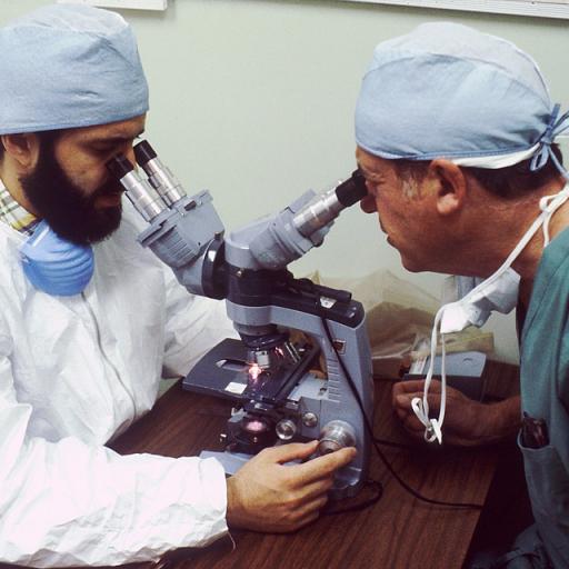 A picture of two man looking into a microscope. 